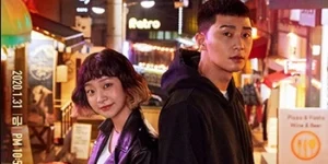 박서준,김다미가 등을 대고 시장 골목길을 배경으로 서서 앞을 보고 있다.